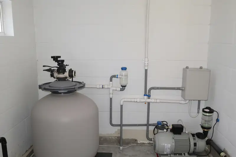 Local technique de piscine avec filtre à sable et vanne multivoies, pompe de filtration au pied du mur et coffret électrique