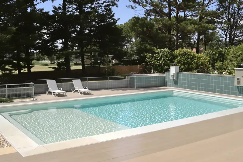 Piscine coque de 7 mètres sur 3 avec plage immergée et deux transats posés dans l’eau peu profonde