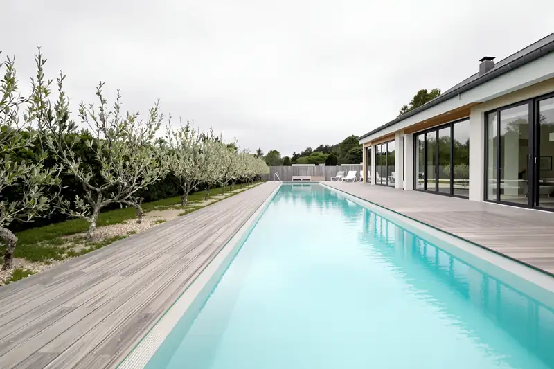 Couloir de nage de 12 mètres longeant une terrasse en bois et une rangée d’oliviers