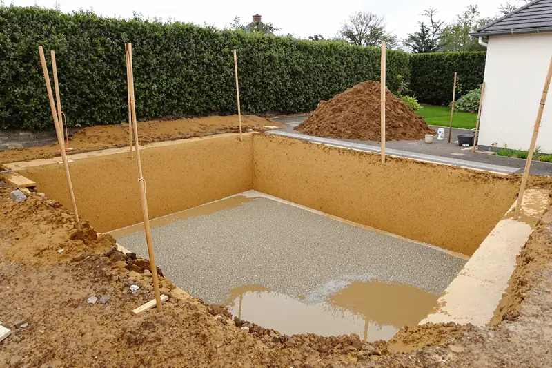 Fouille rectangulaire pour une piscine dans un sol argileux, avec piquets et cordeau d’implantation